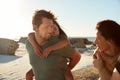 Mid adult white parents piggybacking their kids on a sunny beach, looking at each other, close up Royalty Free Stock Photo