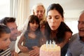 Mid adult white woman blowing out candles on birthday cake watched by her family, close up Royalty Free Stock Photo