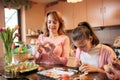 Mid adult woman decorating and painting Easter eggs with her teenage daughter Royalty Free Stock Photo