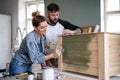 Mid adults couple painting furniture indoors at home, relocation and diy concept. Royalty Free Stock Photo