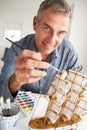 Mid age man painting a model ship at home