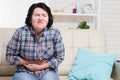 Mid age woman having stomach pain at home, middle-aged woman with stomach pain on sofa Royalty Free Stock Photo