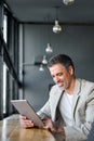 Mid aged business man using digital tablet computer sitting in modern office. Royalty Free Stock Photo