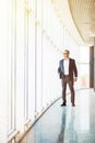 Full length picture of a mid aged business man walking towards the camera and smiling in office building Royalty Free Stock Photo