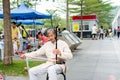 Mid-aged Chinese street musician playing Chinese traditional musical instrument-Erhu Chinese Violin in the Central Park of