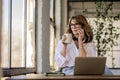 Mid aged entrepreneur female having a call and using notebook at home Royalty Free Stock Photo