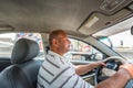 A mid-aged Eyptian male driver driving a car in a street