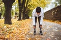 Mid aged fit athletic woman dressed modern running clothes standing and bend over to stretch the back on the footway after jogging