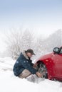 Mid aged male driver mounting car tyre chains