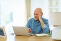 Mid aged man sitting at desk at home and using laptop for work Royalty Free Stock Photo