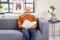 Mid aged man sitting on the sofa at home and reading a book Royalty Free Stock Photo