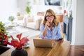 Mid aged woman with earphone, using laptop and having video call at home Royalty Free Stock Photo