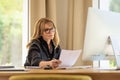 Mid aged woman sitting at desk and using computer for work Royalty Free Stock Photo