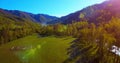 Mid air flight over fresh mountain river and meadow at sunny summer morning. Rural dirt road below. Royalty Free Stock Photo