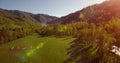 Mid air flight over fresh mountain river and meadow at sunny summer morning. Rural dirt road below. Royalty Free Stock Photo