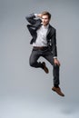 Mid-air style. Handsome young man in full suit jumping against gray background. Royalty Free Stock Photo