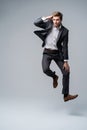 Mid-air style. Handsome young man in full suit jumping against gray background. Royalty Free Stock Photo