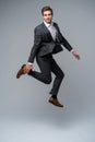 Mid-air style. Handsome young man in full suit jumping against gray background. Royalty Free Stock Photo