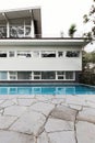 Mid century home exterior with blue tiled swimming pool and crazy paving