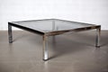 mid-century modern coffee table with smoked glass top and sleek chrome legs