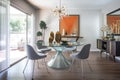 mid-century modern dining room, with sleek and stylish furniture, stunning chandelier, and sleek glass tabletop