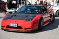 mid-engine V6 Honda NSX. It is red with black carbon fiber mirrors and hood and Recaro seats