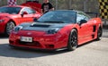 mid-engine V6 Honda NSX. It is red with black carbon fiber mirrors and hood and Recaro seats