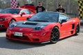 mid-engine V6 Honda NSX. It is red with black carbon fiber mirrors and hood and Recaro seats