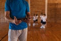 Mid section of basketball coach using digital tablet at basketball court