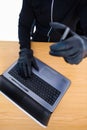 Mid section of a burglar using laptop and smartphone