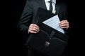 Mid section of businessman in suit holding briefcase with papers