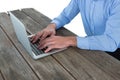 Mid section of businessman using laptop at wooden table Royalty Free Stock Photo