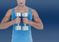 Mid section of caucasian fit woman holding a pair of dumbbells against copy space on blue background