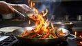 Mid section of chef tossing stir fry over large flame in commercial kitchen