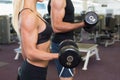 Mid section of couple exercising with dumbbells in gym