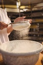 Mid-section of female baker sifting flour through a sieve Royalty Free Stock Photo