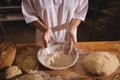 Mid-section of female baker spreading flour in a bowl