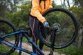 Mid-section of female biker repairing mountain bike