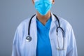 Mid section of female doctor wearing face mask against grey background