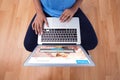 Composite image of mid section of female executive using laptop while sitting on wooden floor Royalty Free Stock Photo