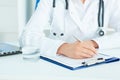 Mid section of a female medicine doctor hand holding silver pen writing something on clipboard closeup. Royalty Free Stock Photo