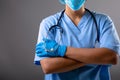 Mid section of female surgeon wearing face mask against grey background