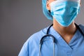 Mid section of female surgeon wearing face mask against grey background