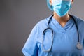 Mid section of female surgeon wearing face mask against grey background