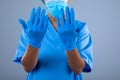 Mid section of female surgeon wearing surgical gloves against grey background