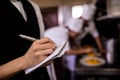 Female waitress noting an order on notepad in kitchen