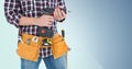 Mid section of handy man with tool belt holding a drill