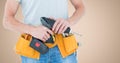 Mid section of handyman holding a drill machine with tool belt around waist Royalty Free Stock Photo