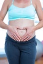 Mid section of pregnant woman making heart shape