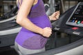 Mid section of pregnant woman running on treadmill